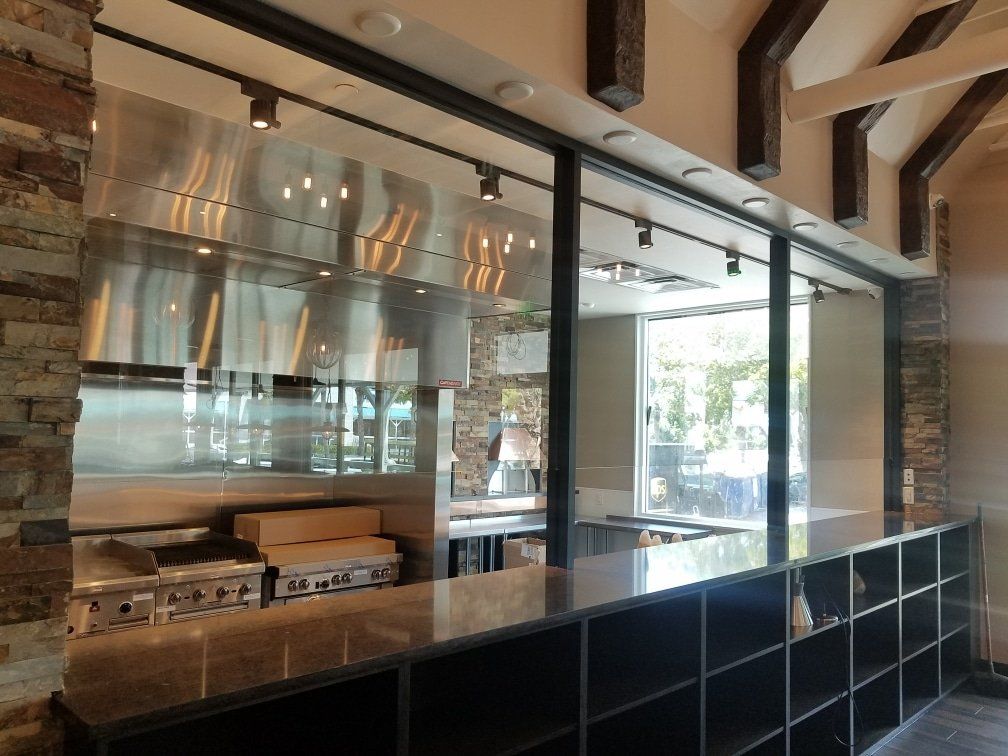Restaurant kitchen with stainless steel hood, stovetop, and a countertop service area.