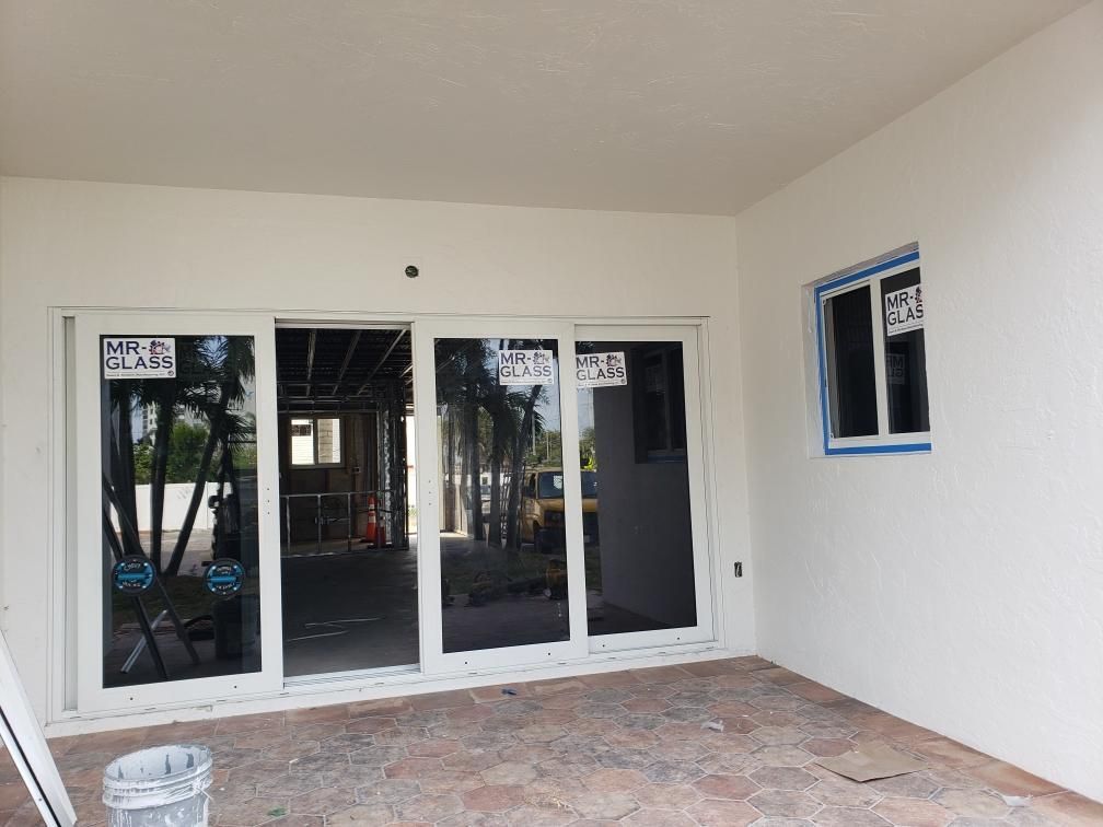 White building exterior with sliding glass doors and a window, under construction.