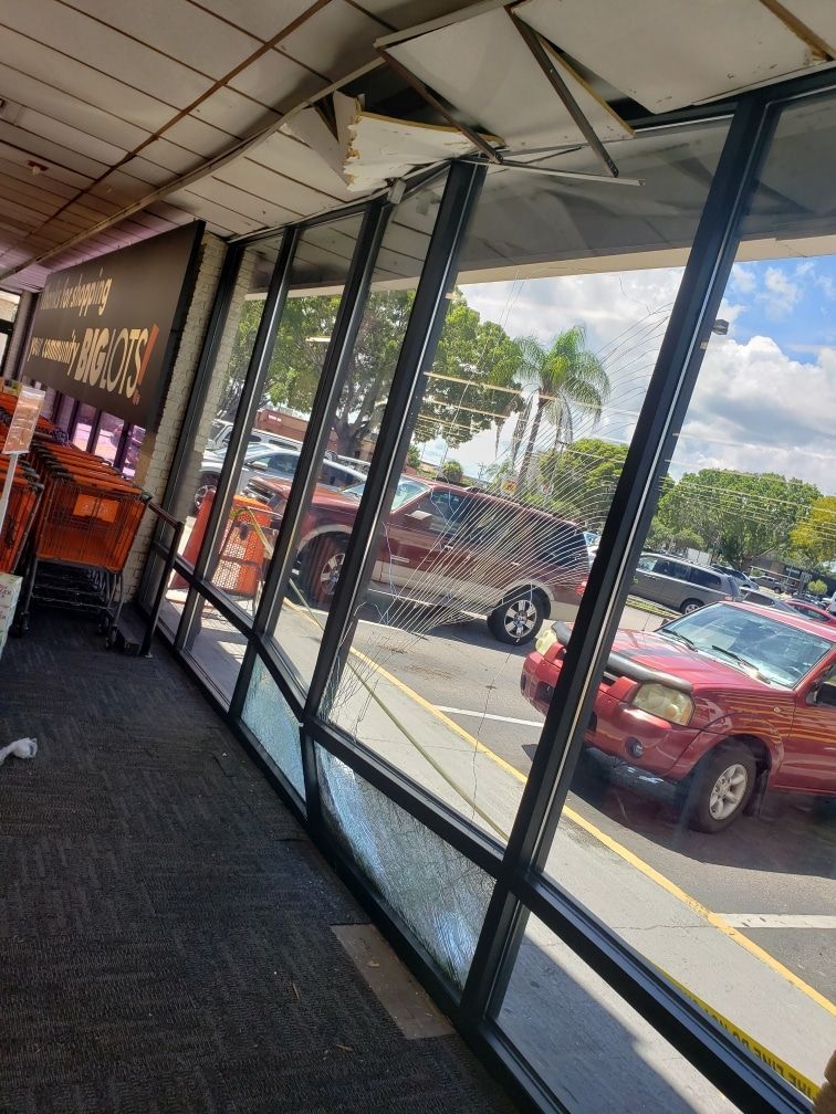 Interior view of a store with a glass wall overlooking a parking lot. Several cars are visible outside.