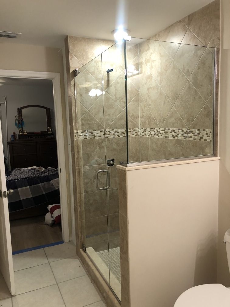Bathroom with tiled shower, glass doors, and a view into a bedroom.