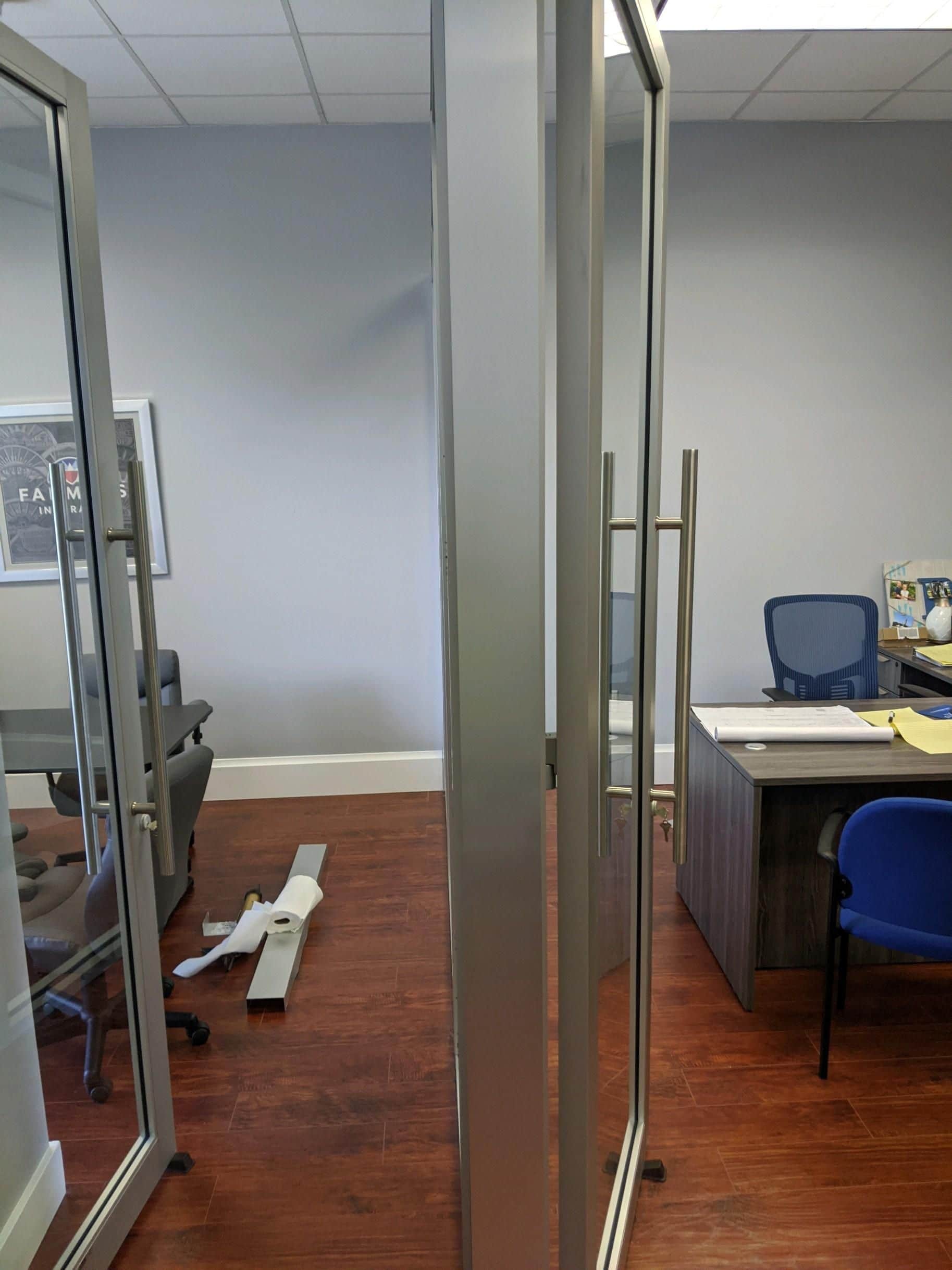 Office interior with glass partitions, a desk, and chairs.