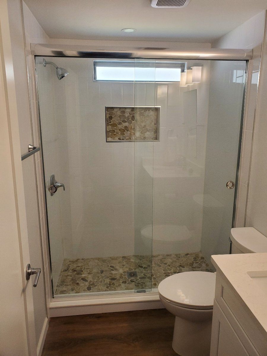Small bathroom with a glass shower, toilet, and white vanity.