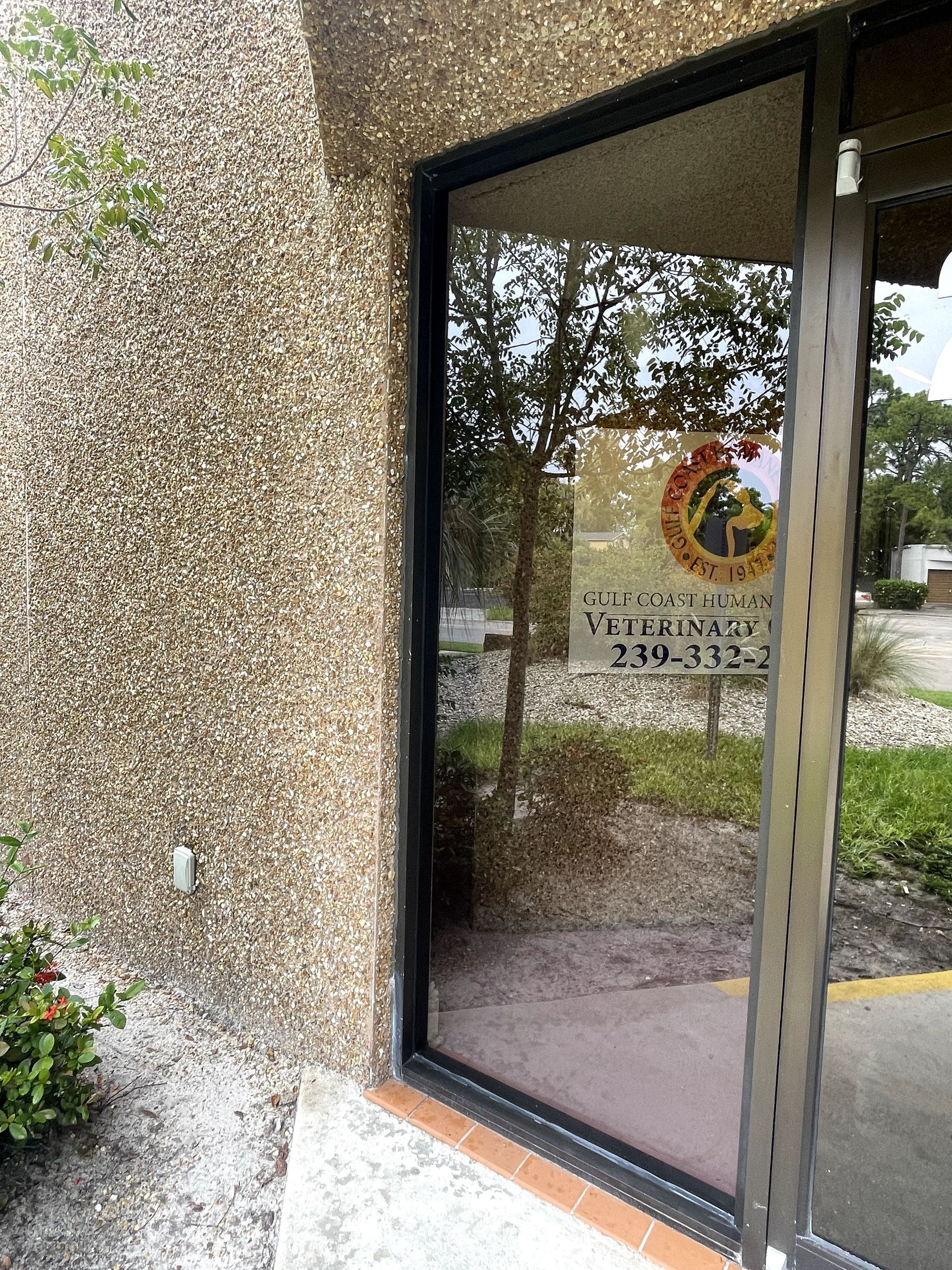 A building entrance with a glass door and a sign visible through the glass.