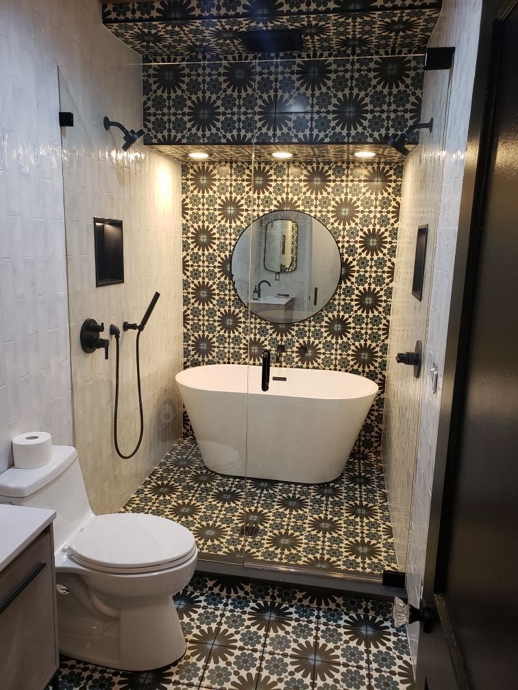 Bathroom with patterned tile, white bathtub, toilet, and black fixtures.