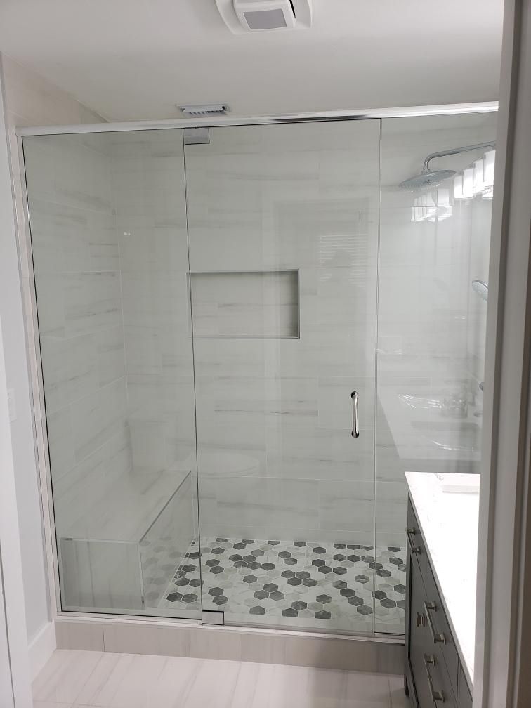 Modern bathroom with glass shower, white tile, hexagon floor, and vanity.