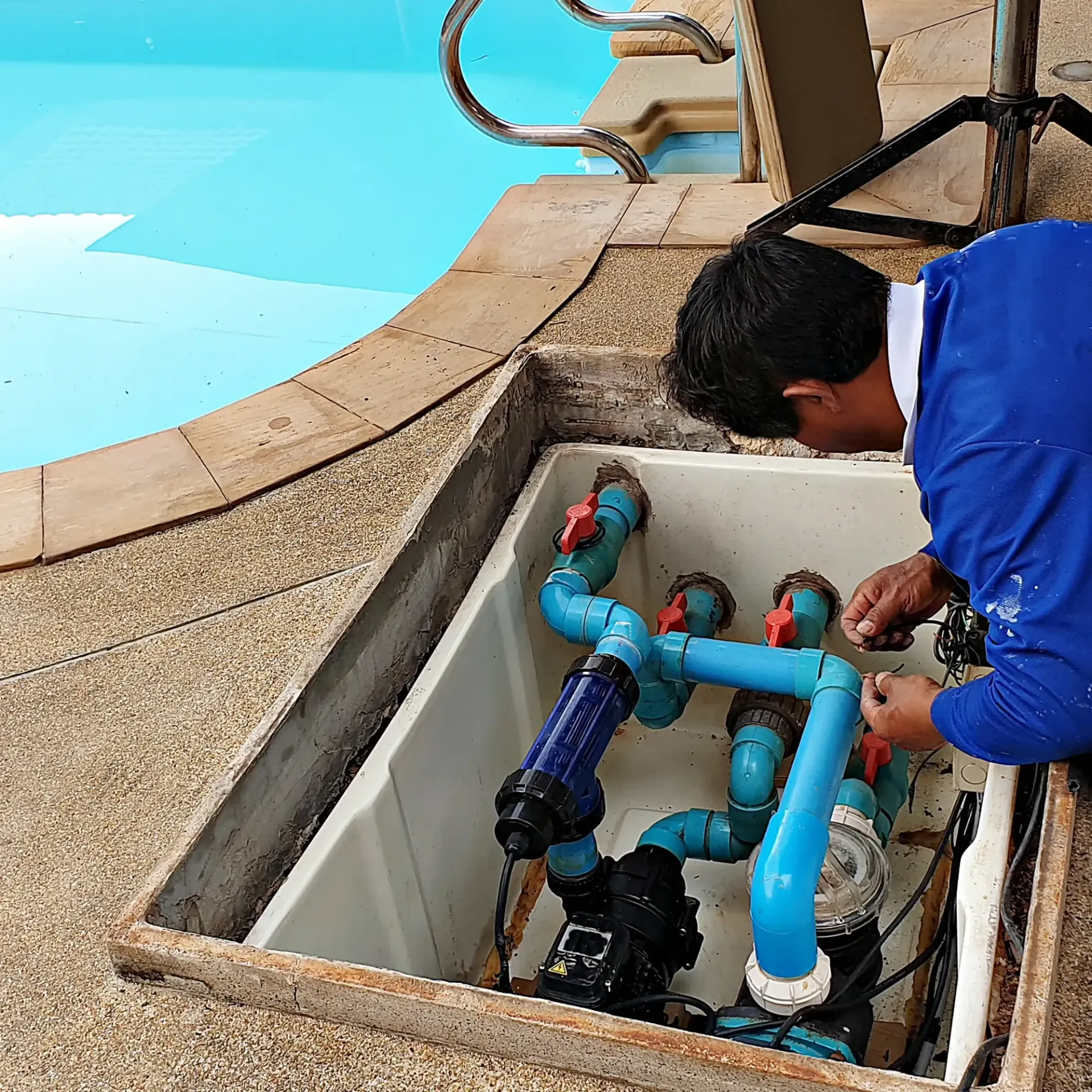 H20 Leak Solution- A man in a blue shirt is working on a swimming pool