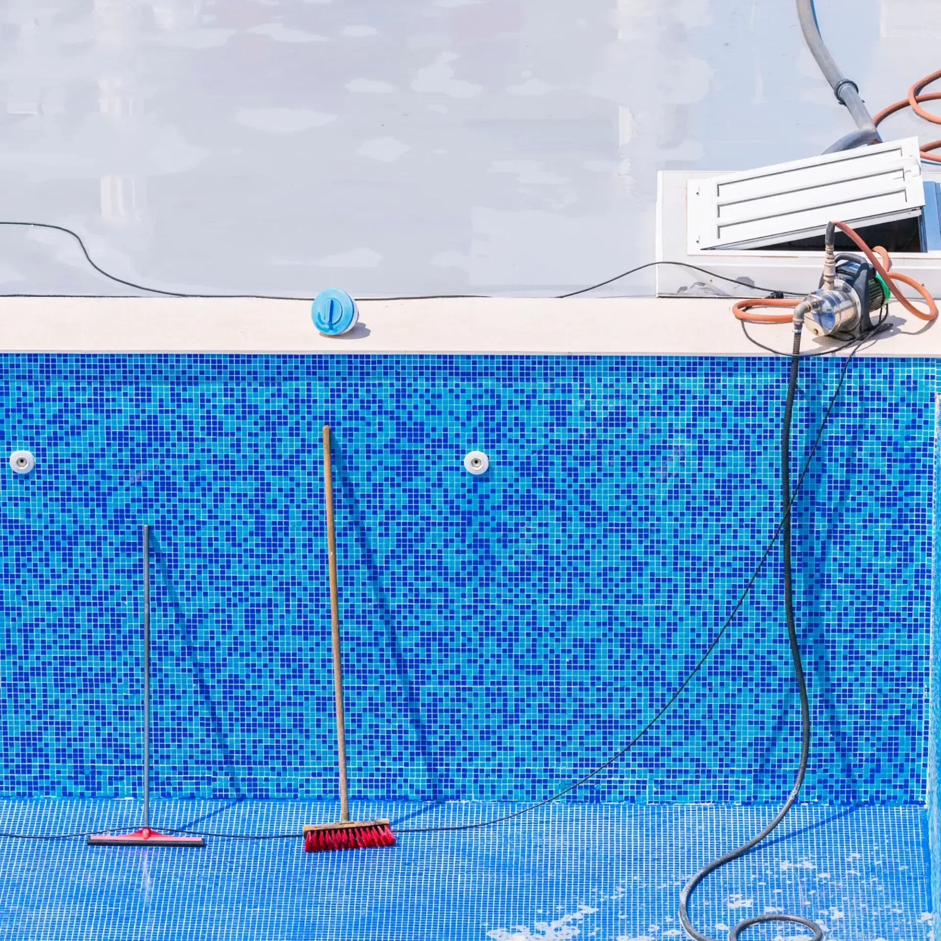 H20 Leak Solution- A swimming pool with blue tiles and a hose connected to it.
