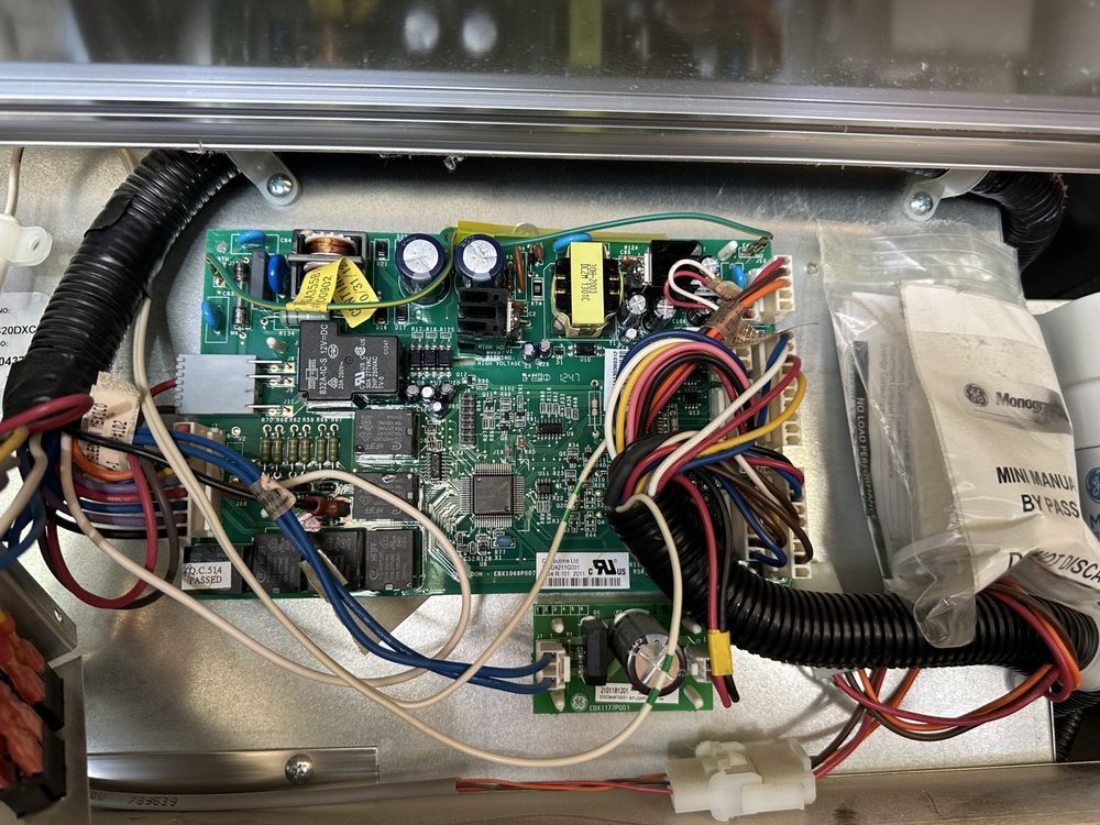 Electronic circuit board with colorful wires and components inside a metallic appliance.