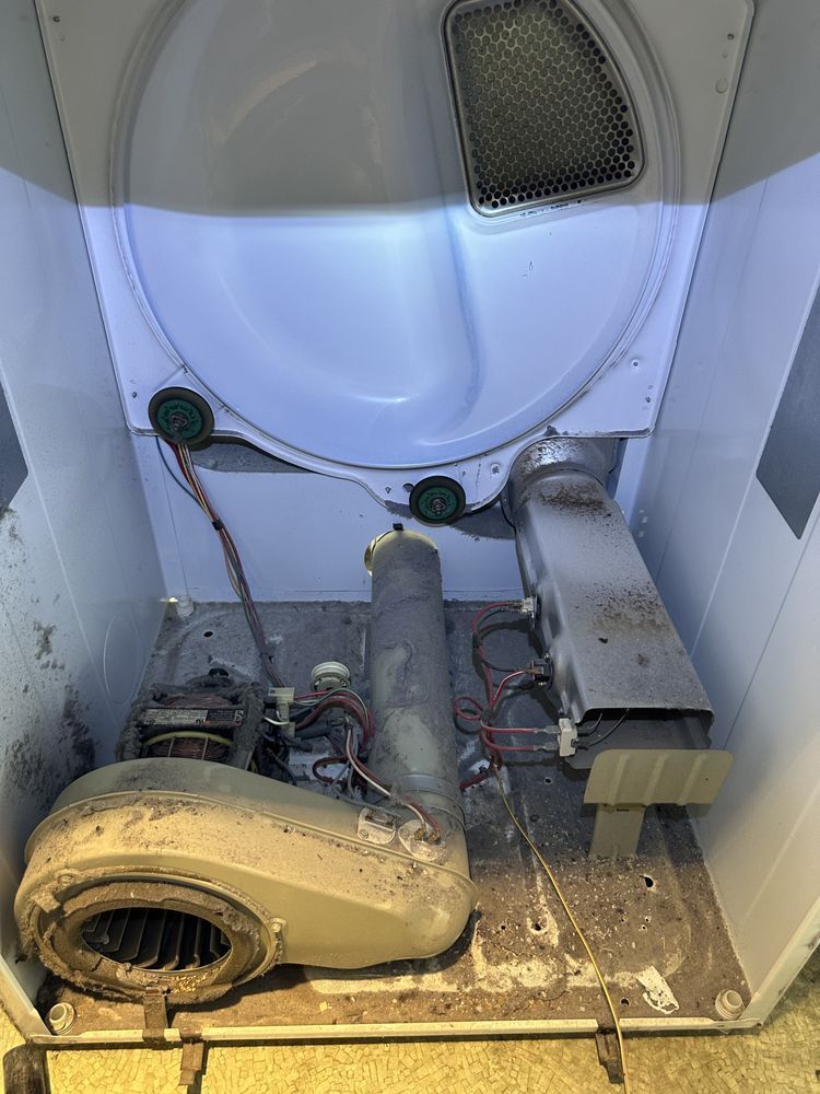 Interior view of a dryer, showing the fan, belt, lint trap, and exhaust vent.