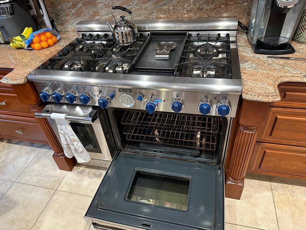 A stainless steel kitchen range with an open oven door, set in a kitchen.