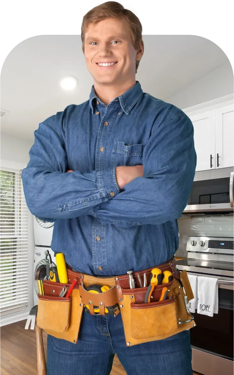 Smiling handyman with arms crossed, wearing a tool belt in a kitchen.