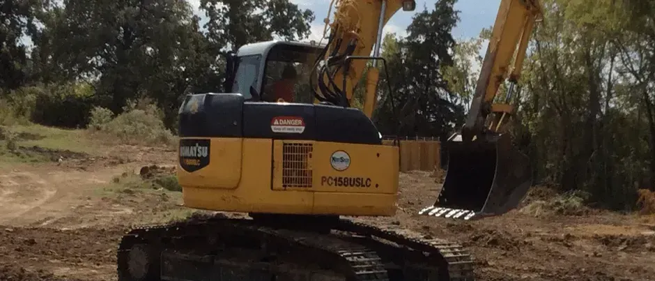 A large yellow excavator is parked on the side of the road.