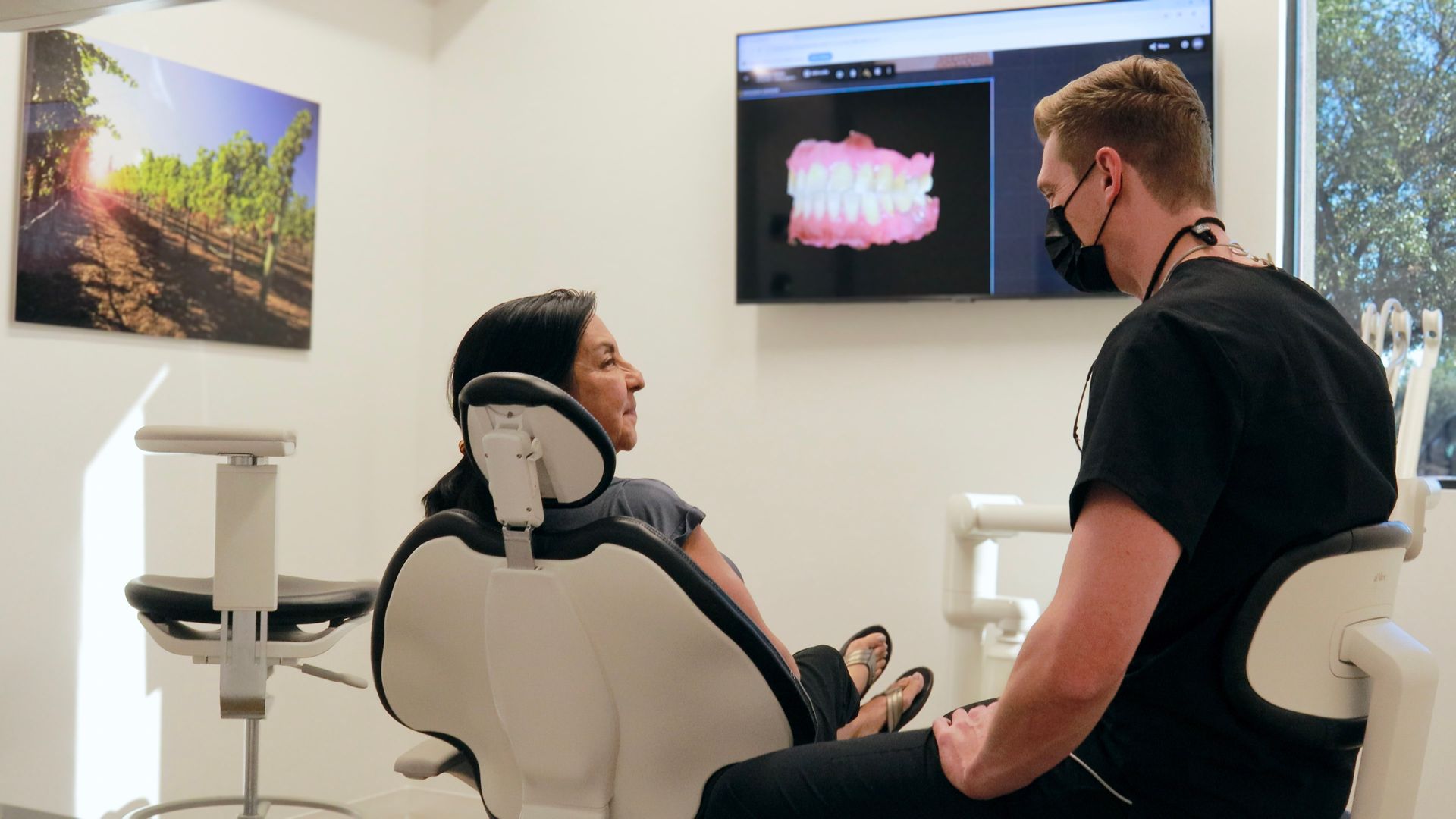 Dentist showing a patient a digital scan of teeth on a monitor in a dental office.