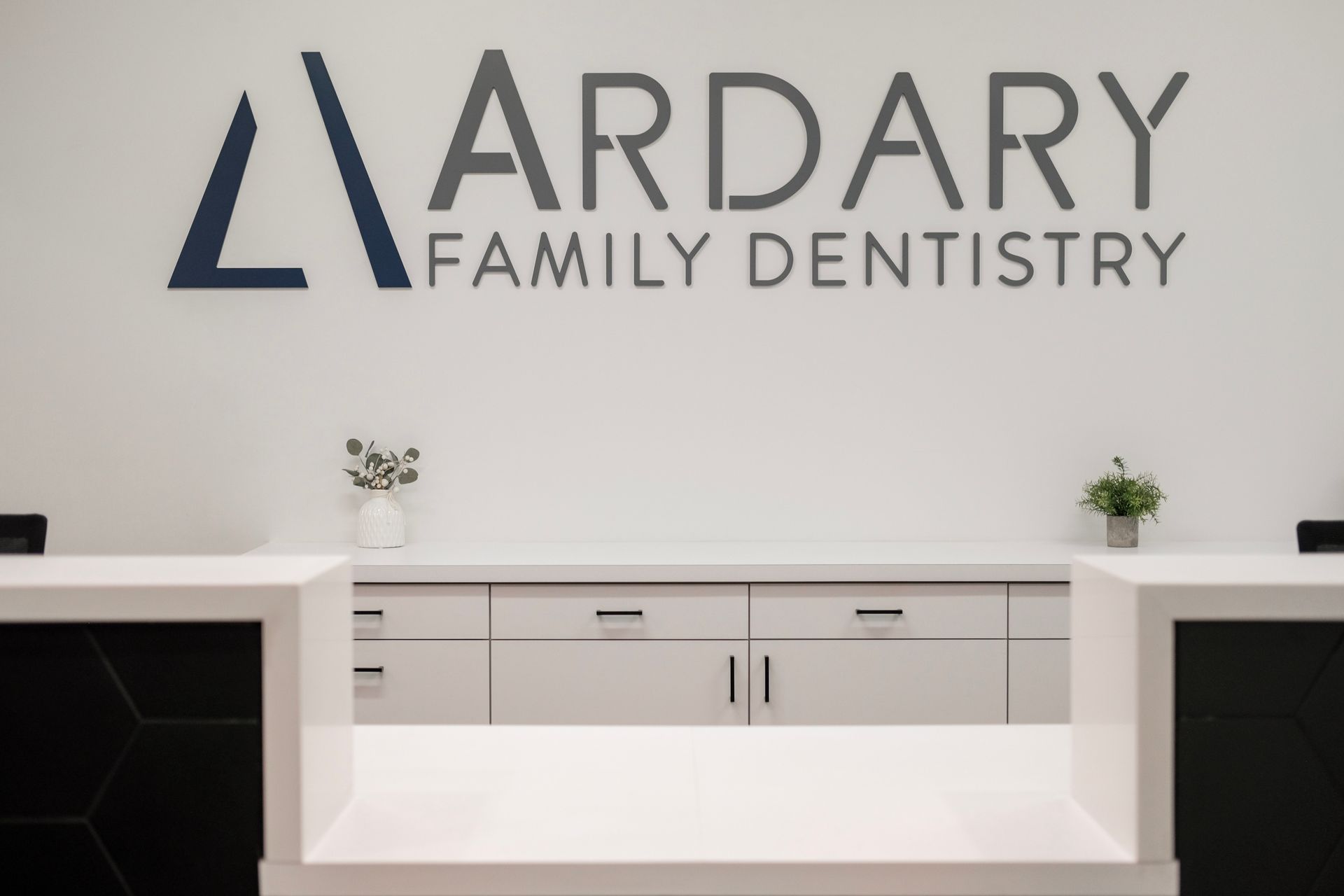 Reception area for Ardary Family Dentistry with white counter and logo above.