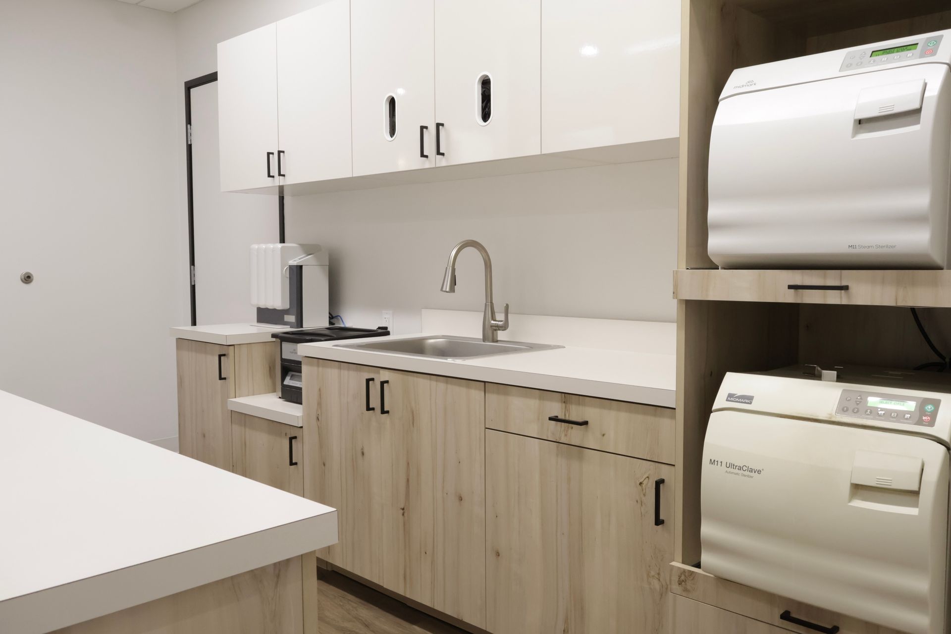 Dental sterilization room with cabinets, sink, and autoclaves.