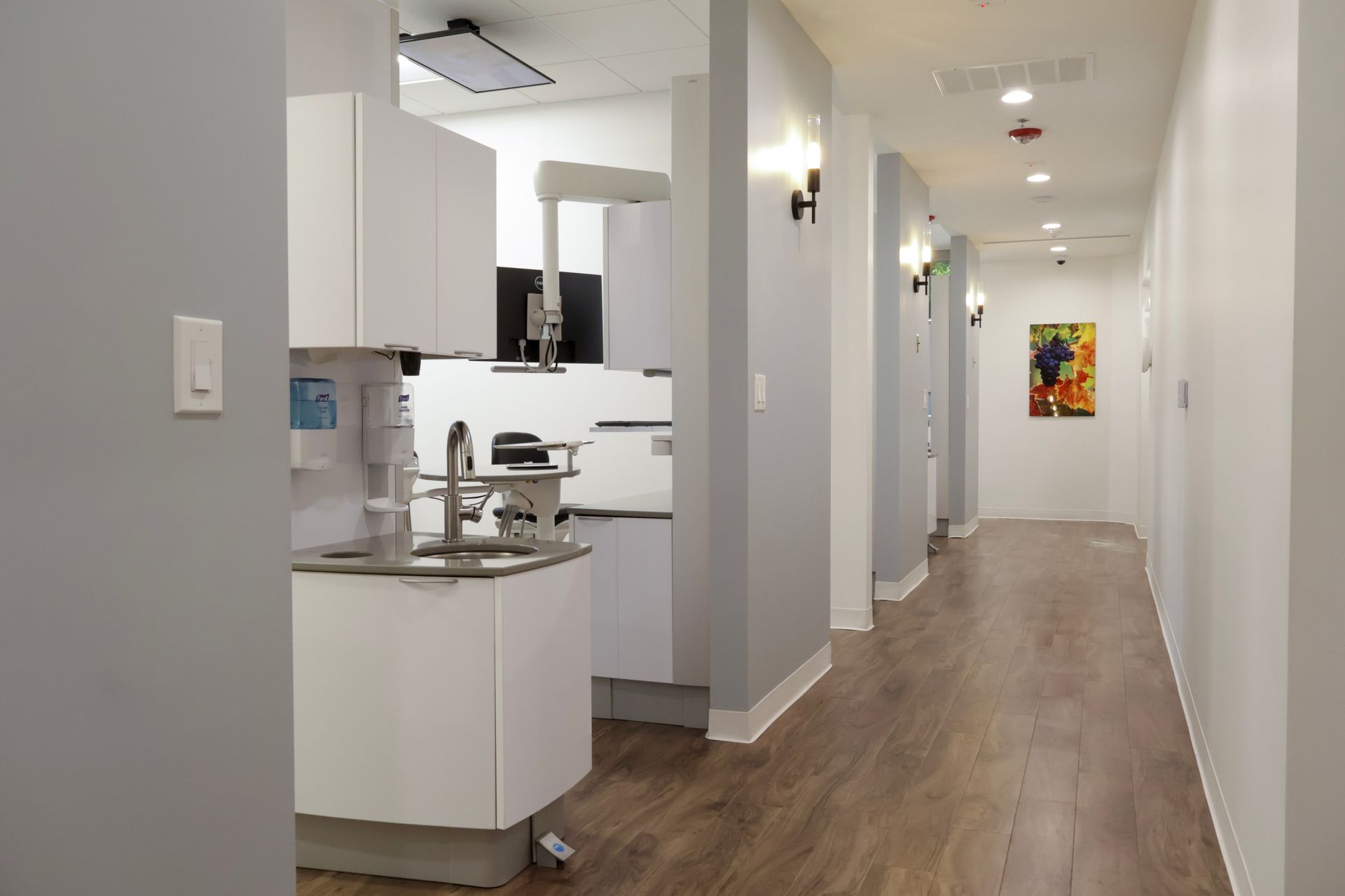 Hallway in a dental office with treatment rooms and a sink area visible.