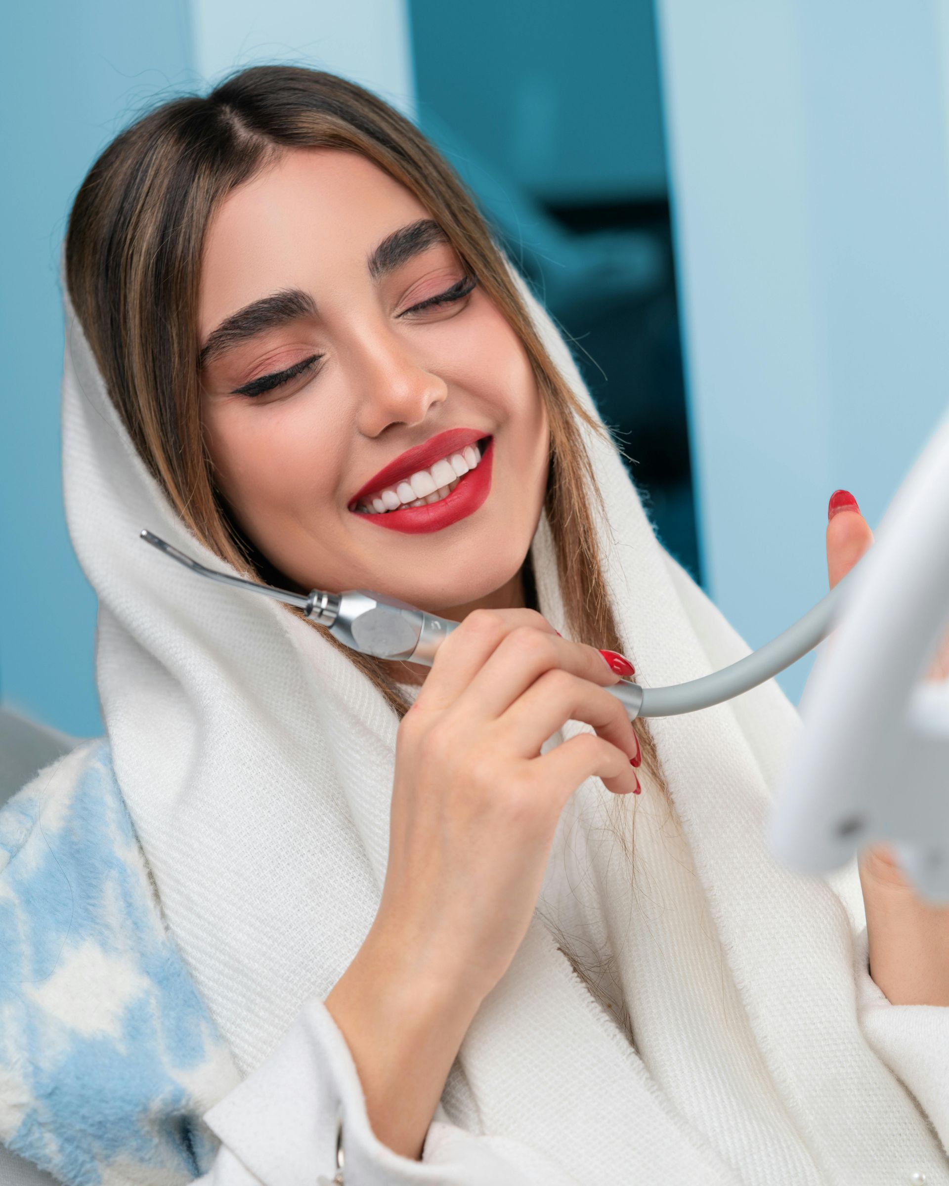 A woman with red lipstick is smiling while holding a cord