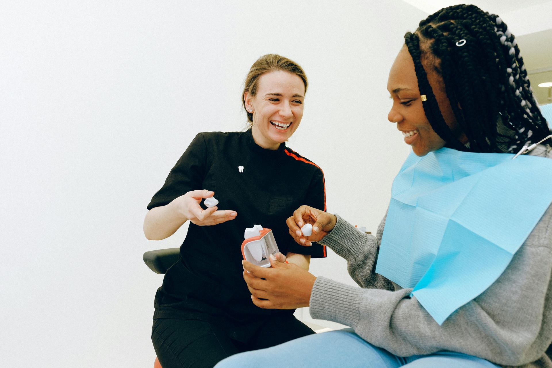 A woman is sitting in a dental chair talking to a dentist.