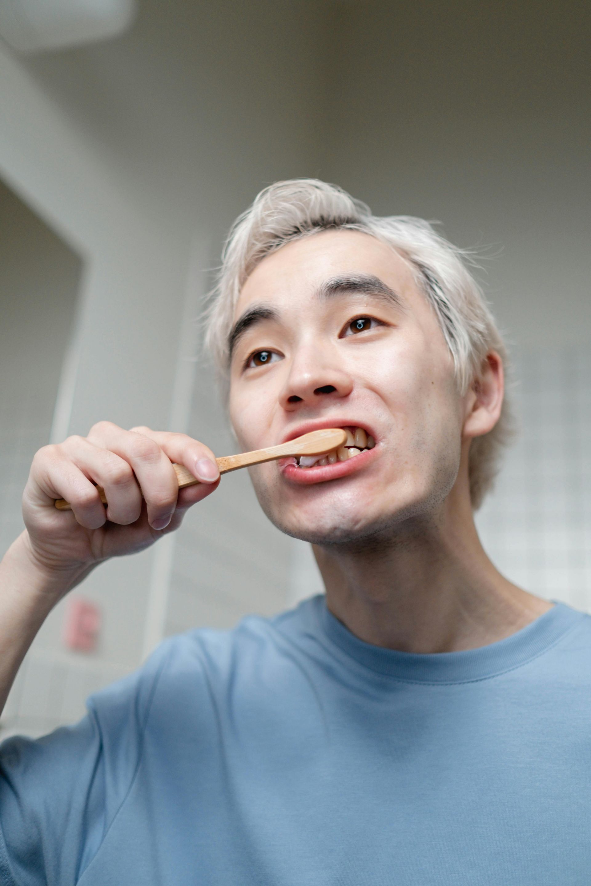 A man is brushing his teeth with a wooden toothbrush.