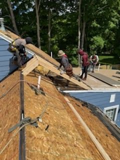 A group of men are working on the roof of a house.