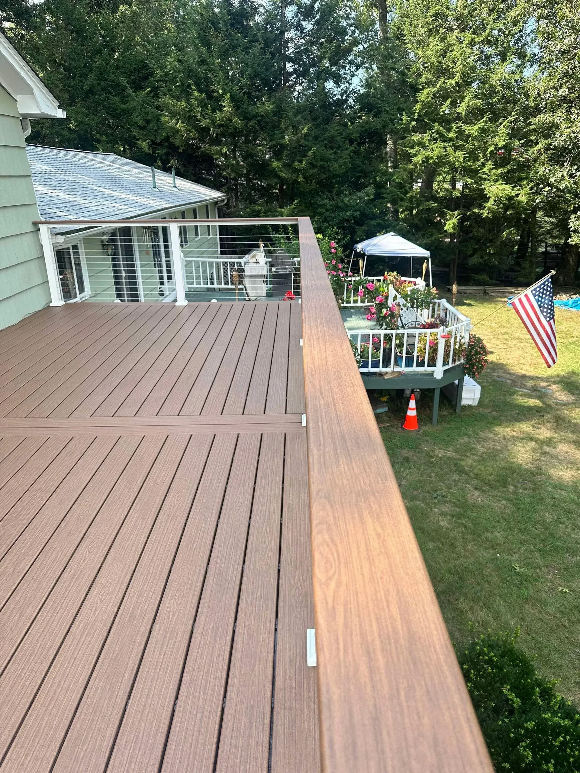 A wooden deck with a railing is in the backyard of a house.