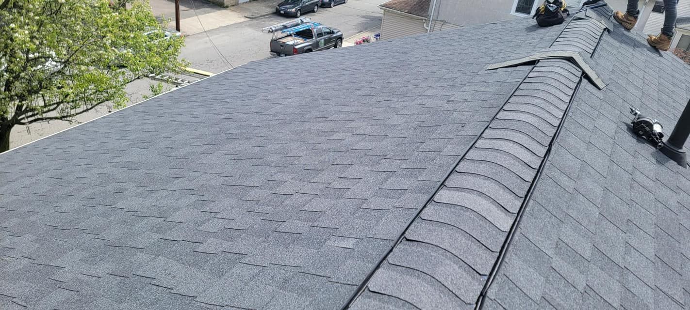A person is standing on top of a roof with a ladder attached to it.