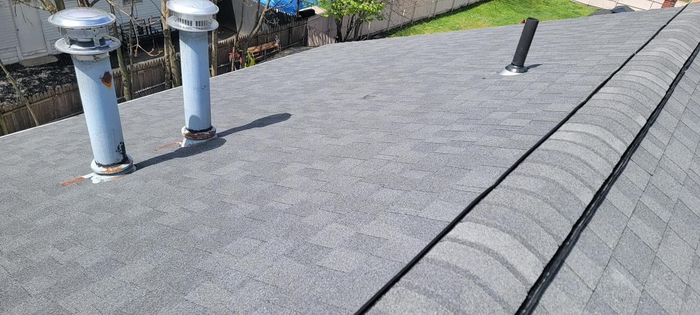 A close up of a roof with two chimneys on it.