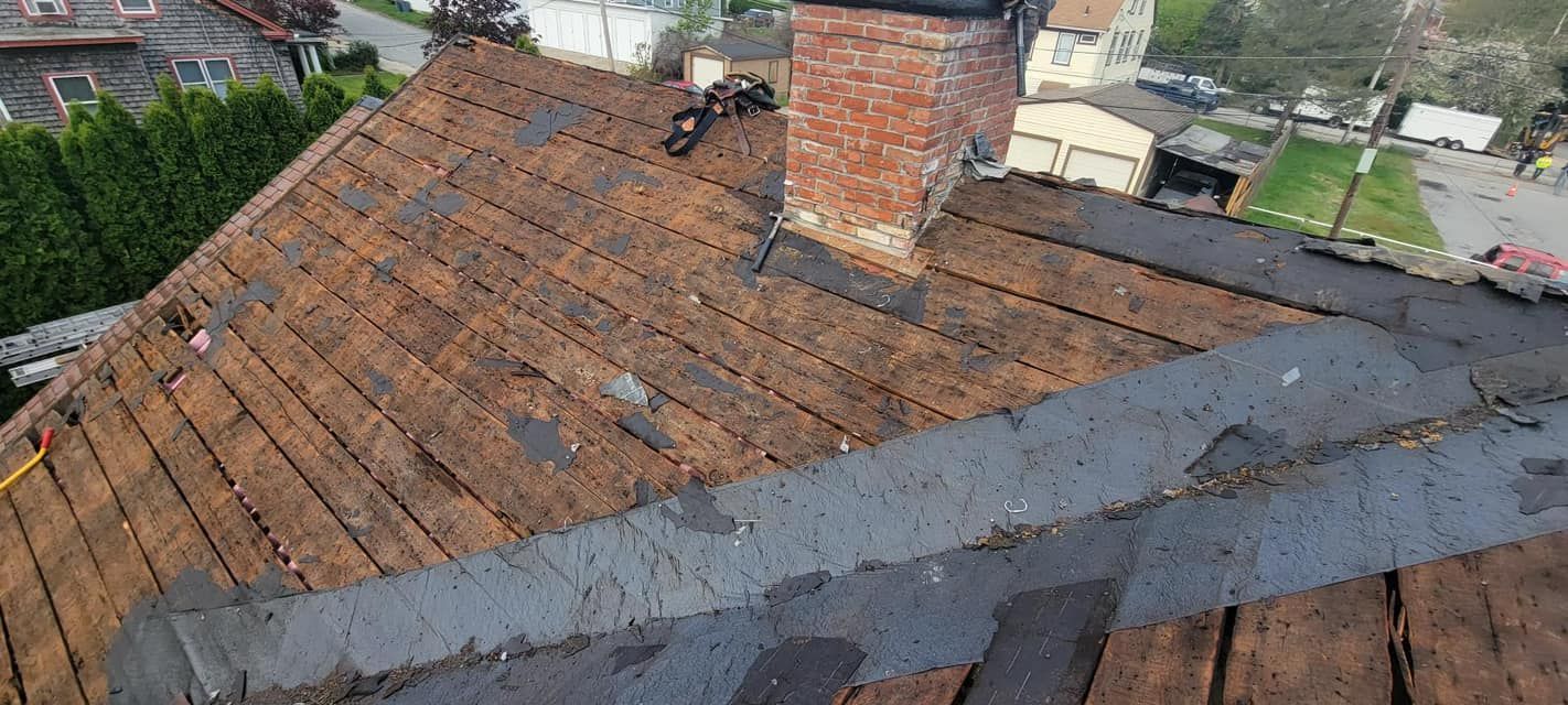 An aerial view of a roof with a chimney in the background.