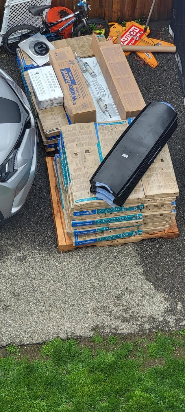 A pile of wood is sitting on the side of the road next to a car.