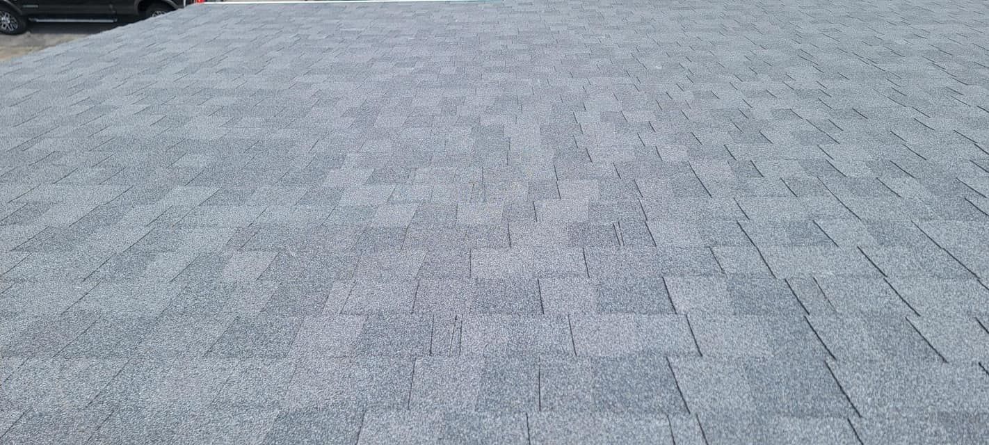A gray brick driveway with a car parked in the background.