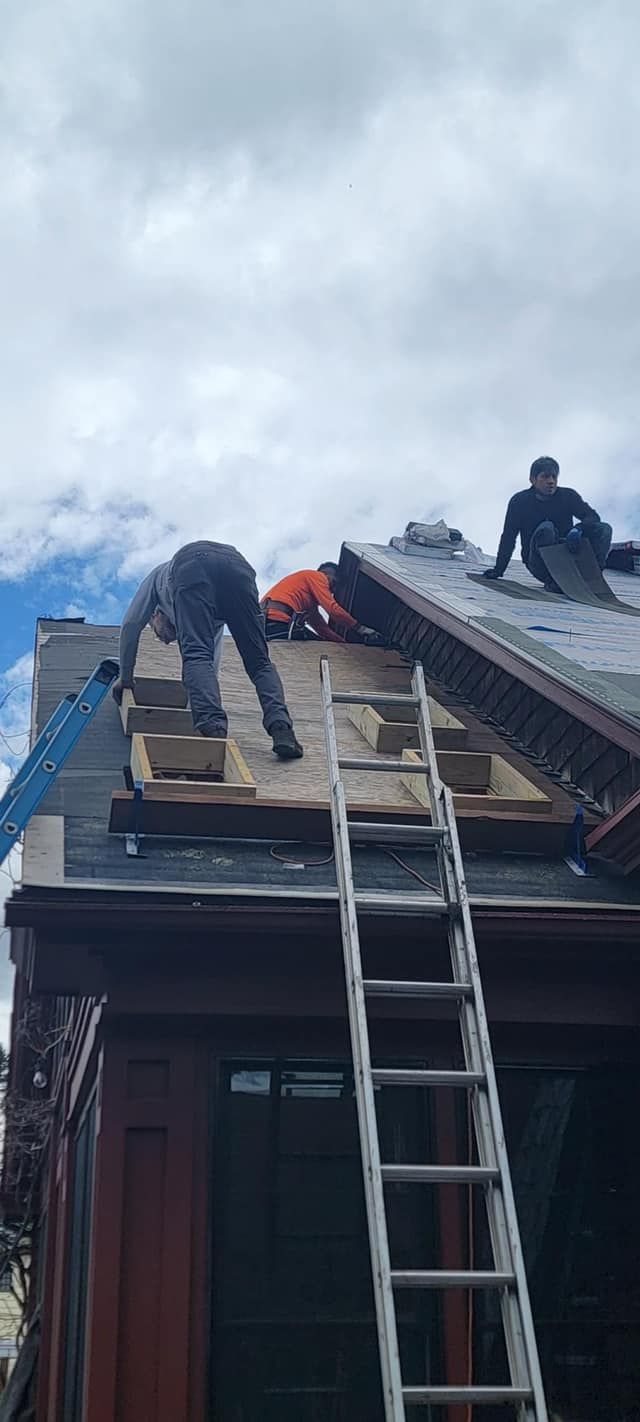 A group of men are working on the roof of a building.