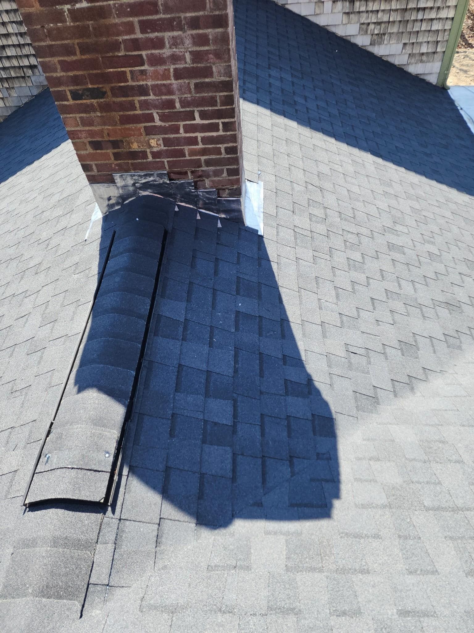 A brick chimney with a blue roof and a shadow on the ground.