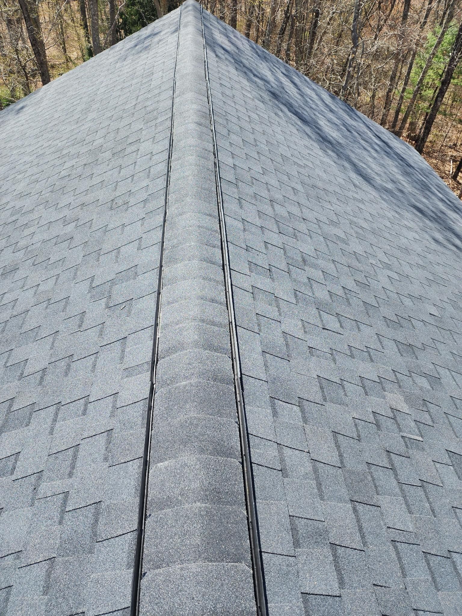 A close up of a roof with shingles on it in the woods.