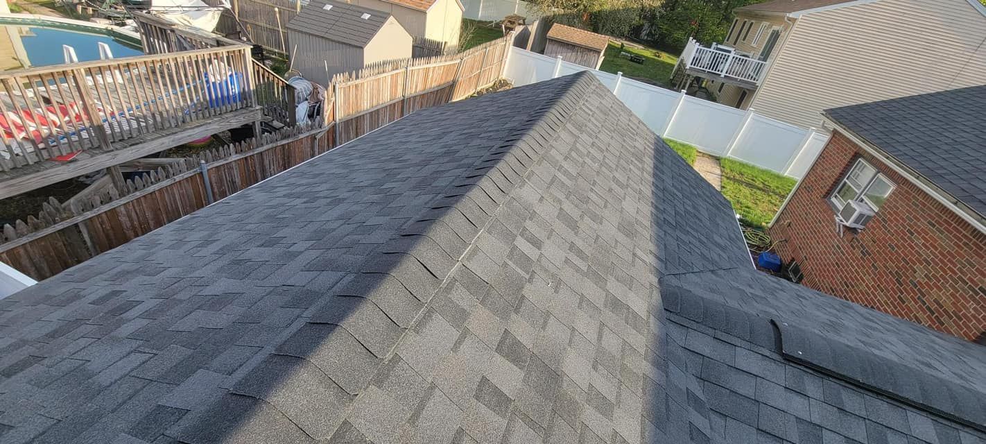 An aerial view of a roof of a house with a pool in the background.