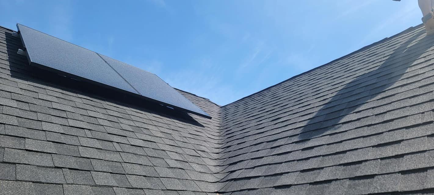 A roof with solar panels on it and a blue sky in the background.