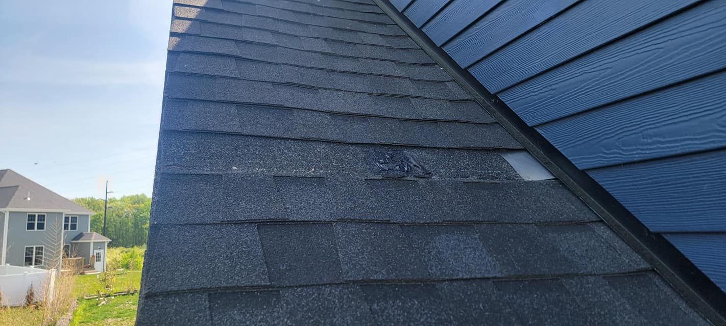A close up of a roof with a blue house in the background.