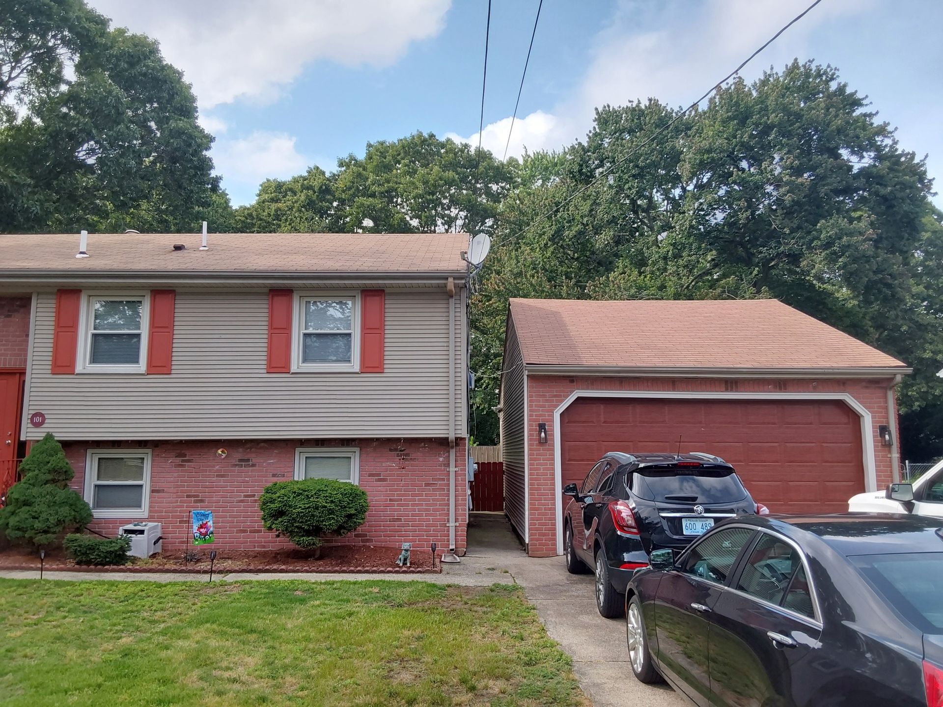 Two cars are parked in front of a house with a garage