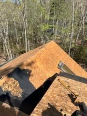 A person is working on a roof in the woods.