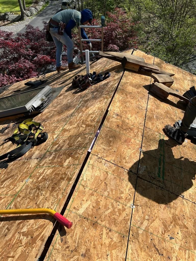 A man is standing on top of a wooden roof.