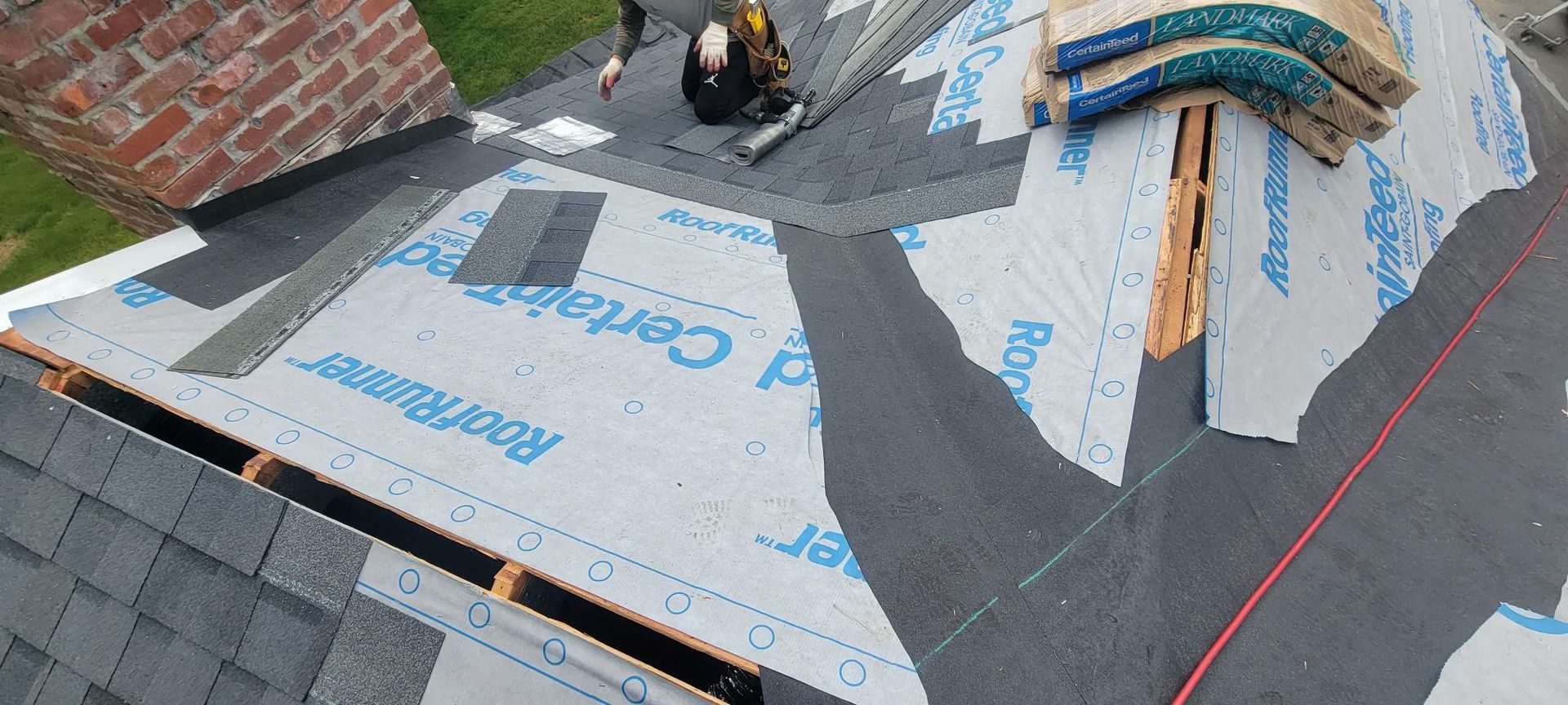 A man is working on a roof with shingles.
