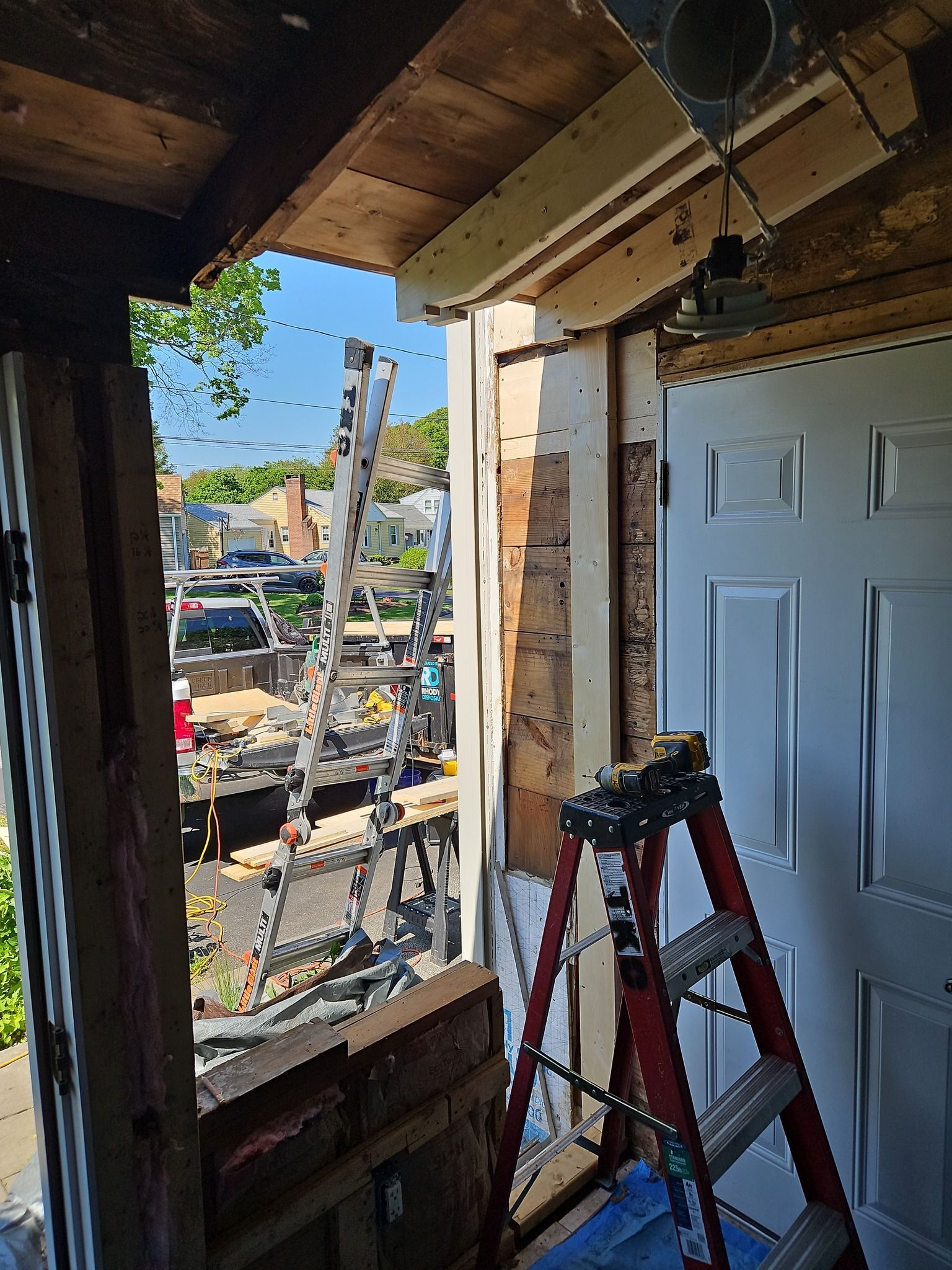 A ladder is sitting in front of a door that is being remodeled.