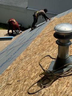 Two men are working on the roof of a house.