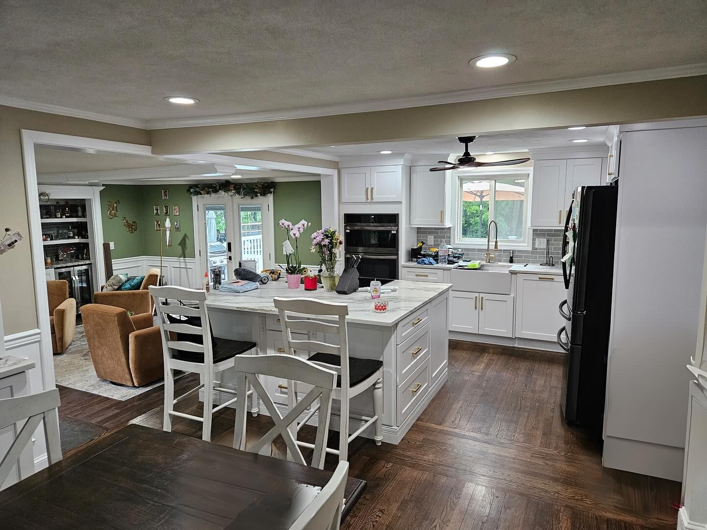 A kitchen with white cabinets , a large island , a table and chairs.