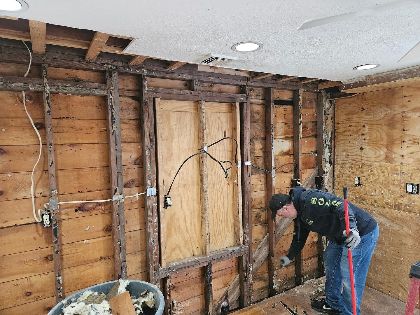 A man is working on a wooden wall in a room.