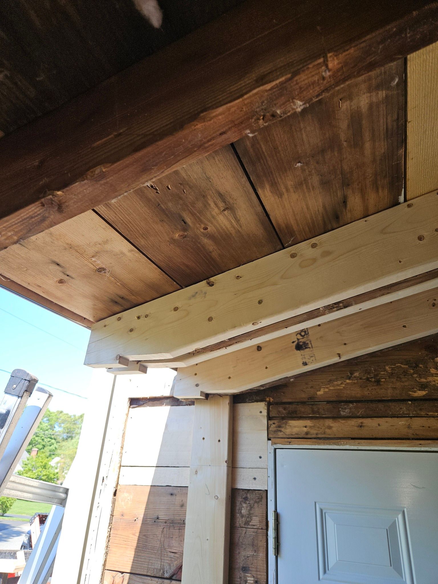 A wooden ceiling with a white door in the background