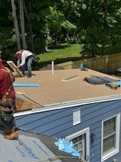 A man is working on the roof of a blue house.