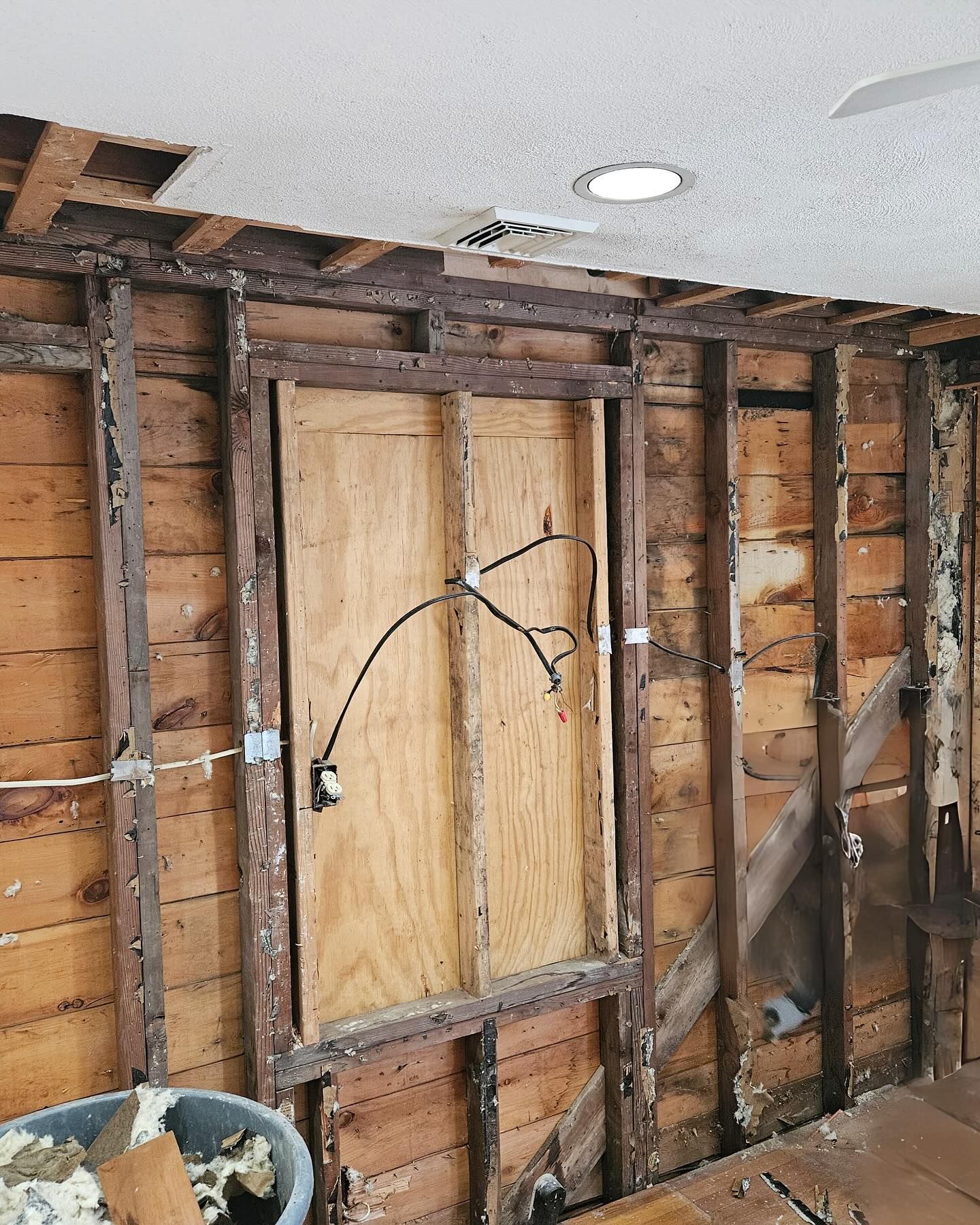 A wooden wall with a hole in the ceiling is being remodeled.