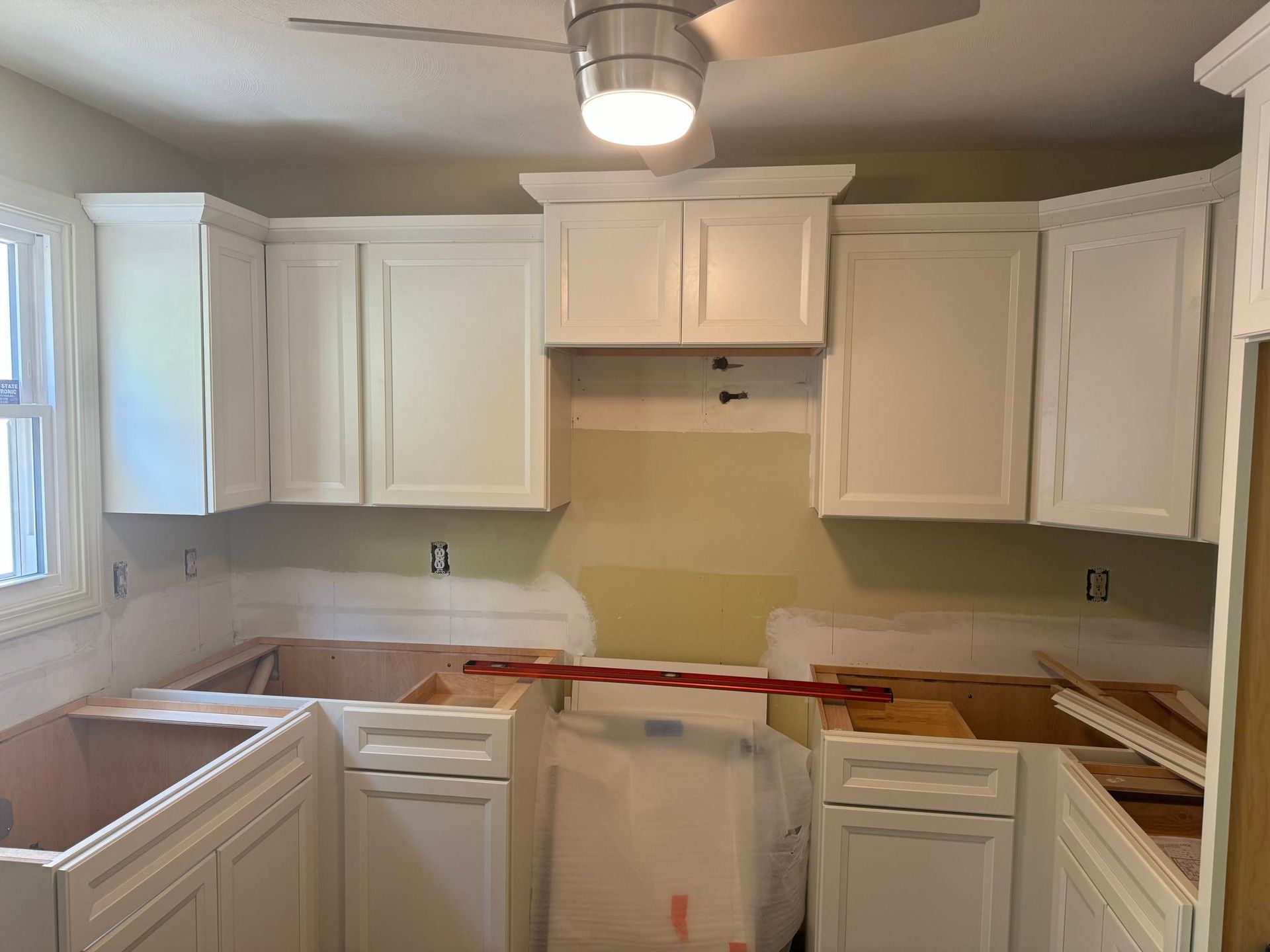 A kitchen with white cabinets and a ceiling fan.