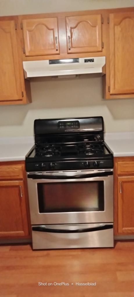 A stove and oven in a kitchen with wooden cabinets.