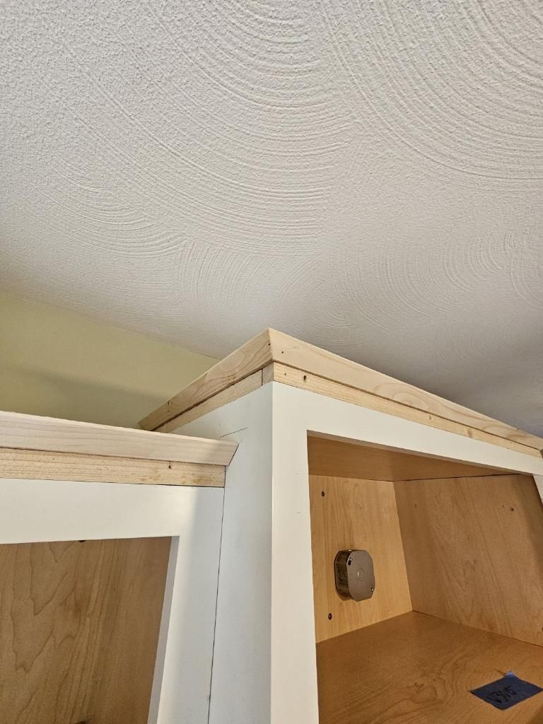 A close up of a corner of a cabinet with a ceiling in the background.